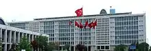 A mid-rise glass-paned office building, with an array of Turkish flags in the front.