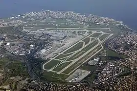 An aerial view of an airport with three runways and several taxiways arranged around a terminal