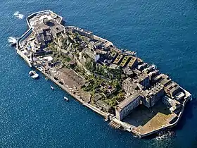 構成遺産の一つ、端島（通称「軍艦島」、長崎県長崎市高島町）の全景。1870年（明治3年）に石炭採掘が始まり1974年（昭和49年）まで操業した。明治期の生産施設の遺構や、1897年（明治30年）から1931年（昭和6年）にかけての6度に亘る埋め立ての跡が残る後藤惠之輔・坂本道徳 『軍艦島の遺産 : 風化する近代日本の象徴』38頁・158頁、長崎新聞社、2005年、ISBN 9784931493537。