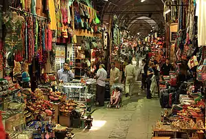 Goods overflow out of storefronts, leaving a narrow passageway where shoppers move about.