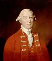 A half-height portrait of Carleton.  He wears a red coat with vest, over a white shirt with ruffles.  His white hair is drawn back, and he faces front with a neutral expression.