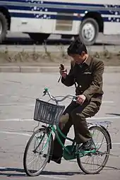 ながら運転の一例。自転車の運転中に携帯電話を手に持ち、画面に意識を向けている。