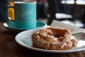 An old-fashioned doughnut with a sugar glaze, accompanied with coffee