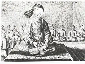 Black-and-white print of a man with small eyes and a thin mustache wearing a robe, a fur hat, and a necklace made with round beads, sitting cross-legged on a three-level platform covered with a rug. Behind him and much smaller are eight men (four on each side) sitting in the same position wearing robes and round caps, as well as four standing men with similar garb (on the left).