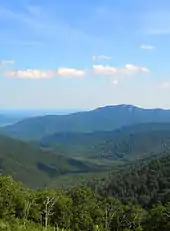 Green tree covered mountains turn blue as the progress toward the horizon.