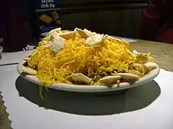 small oval white plate holding partially-eaten 5-way, showing spaghetti, sauce, cheese, and oyster crackers